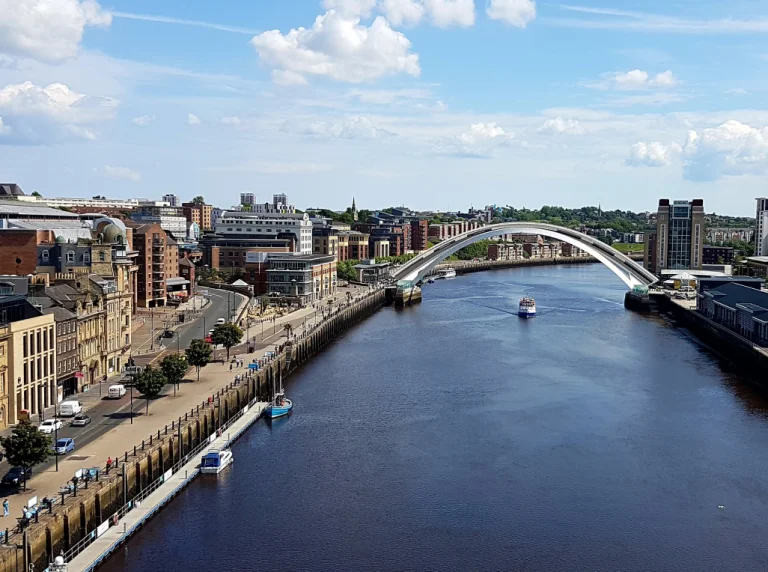 A wide view shot of the Millennium Bridge and a boat sailing underneath it
